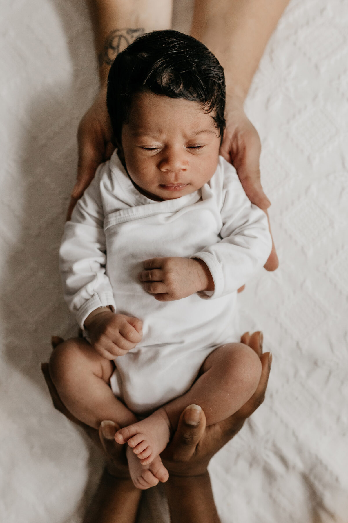 newborn in handen van papa en mama thuis